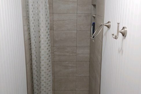 a bathroom with a shower, toilet, and shower curtain.