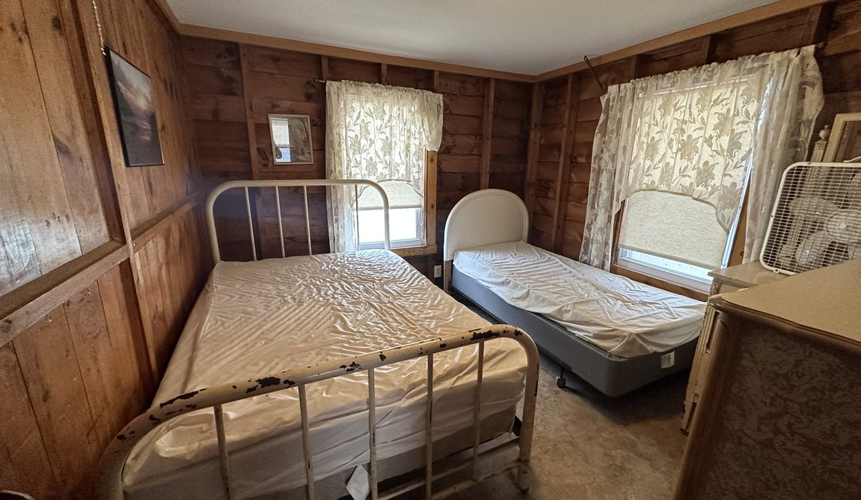 a couple of beds in a room with wooden walls.