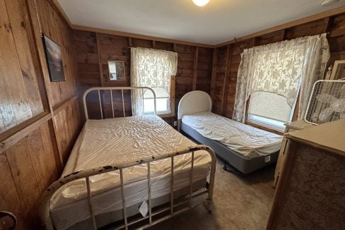 a couple of beds in a room with wooden walls.
