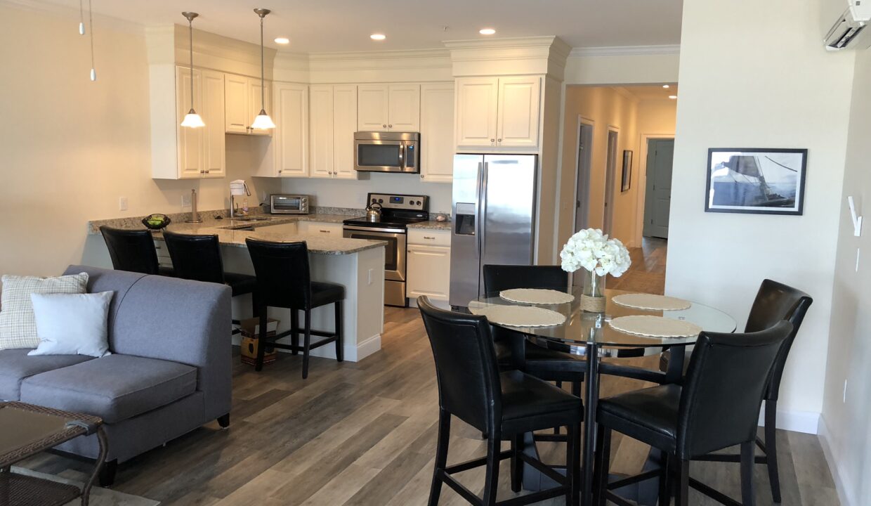 a living room and dining room combination with a kitchen in the background.