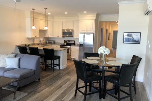 a living room and dining room combination with a kitchen in the background.