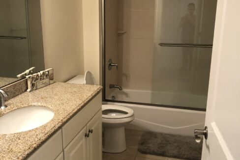 a bathroom with a toilet, sink, and shower.