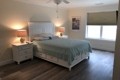 a bedroom with a bed, two nightstands and a ceiling fan.