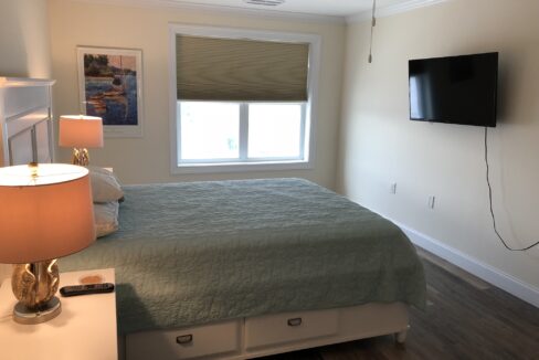 a bed room with a neatly made bed and a flat screen tv.