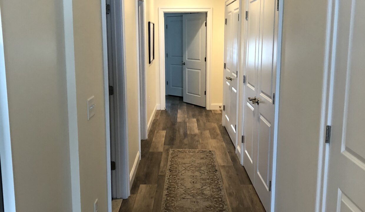 a long hallway with wooden floors and white doors.