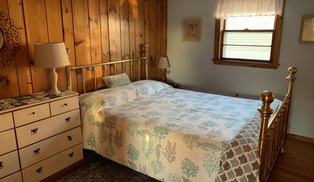 a bedroom with a bed, dresser, and window.
