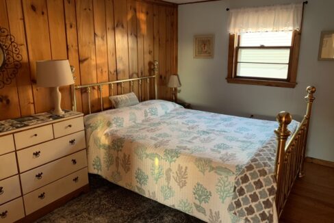 a bedroom with a bed, dresser, and window.