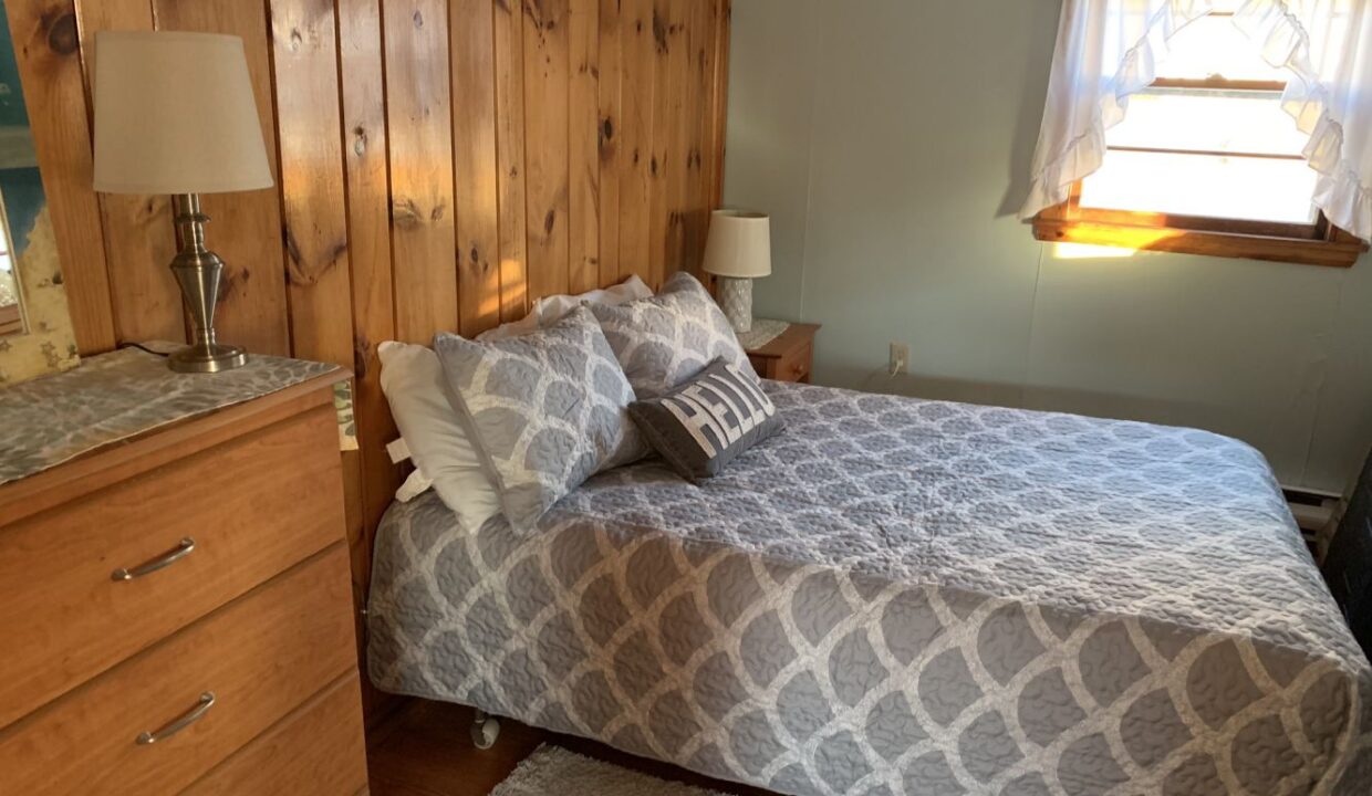 a bedroom with a bed, dresser and mirror.