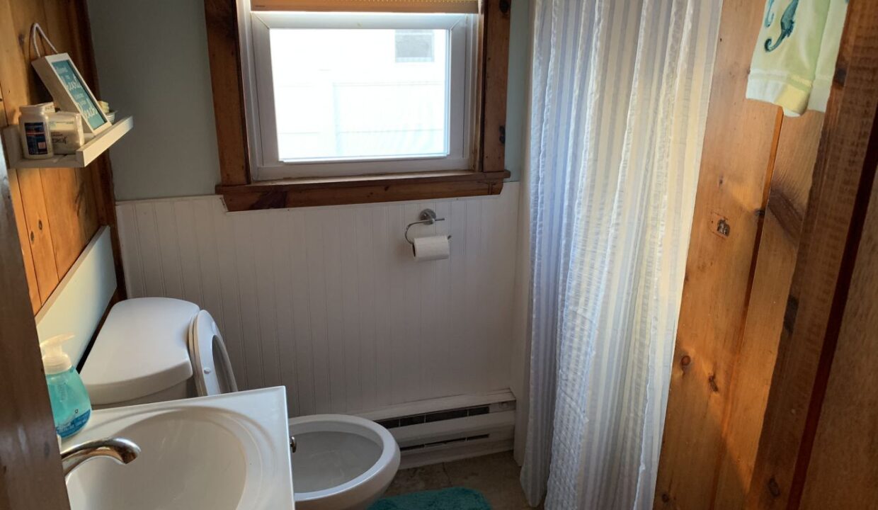 a bathroom with a sink, toilet and a window.