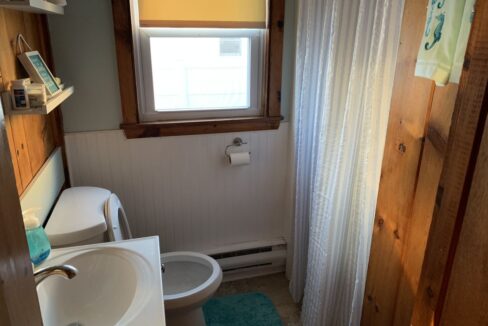 a bathroom with a sink, toilet and a window.