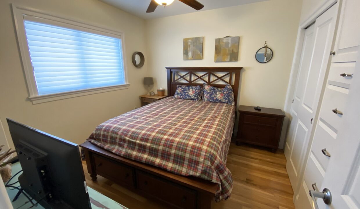 a bed room with a neatly made bed and a flat screen tv.