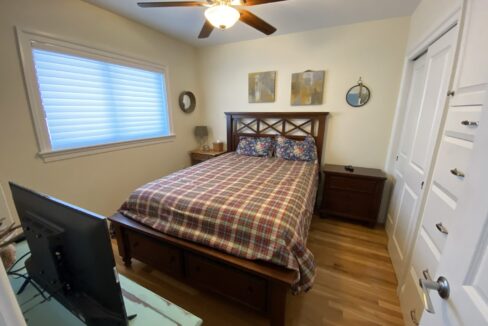 a bed room with a neatly made bed and a flat screen tv.