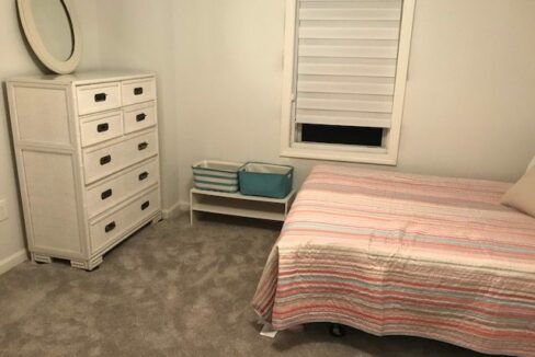 a bedroom with a bed, dresser and mirror.