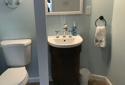 a bathroom with a toilet, sink and mirror.