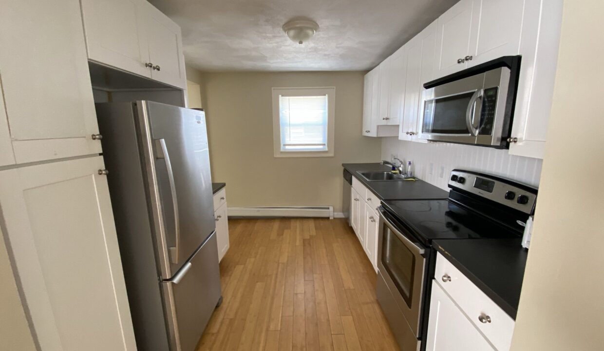 a kitchen with white cabinets and black counter tops.