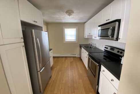 a kitchen with white cabinets and black counter tops.