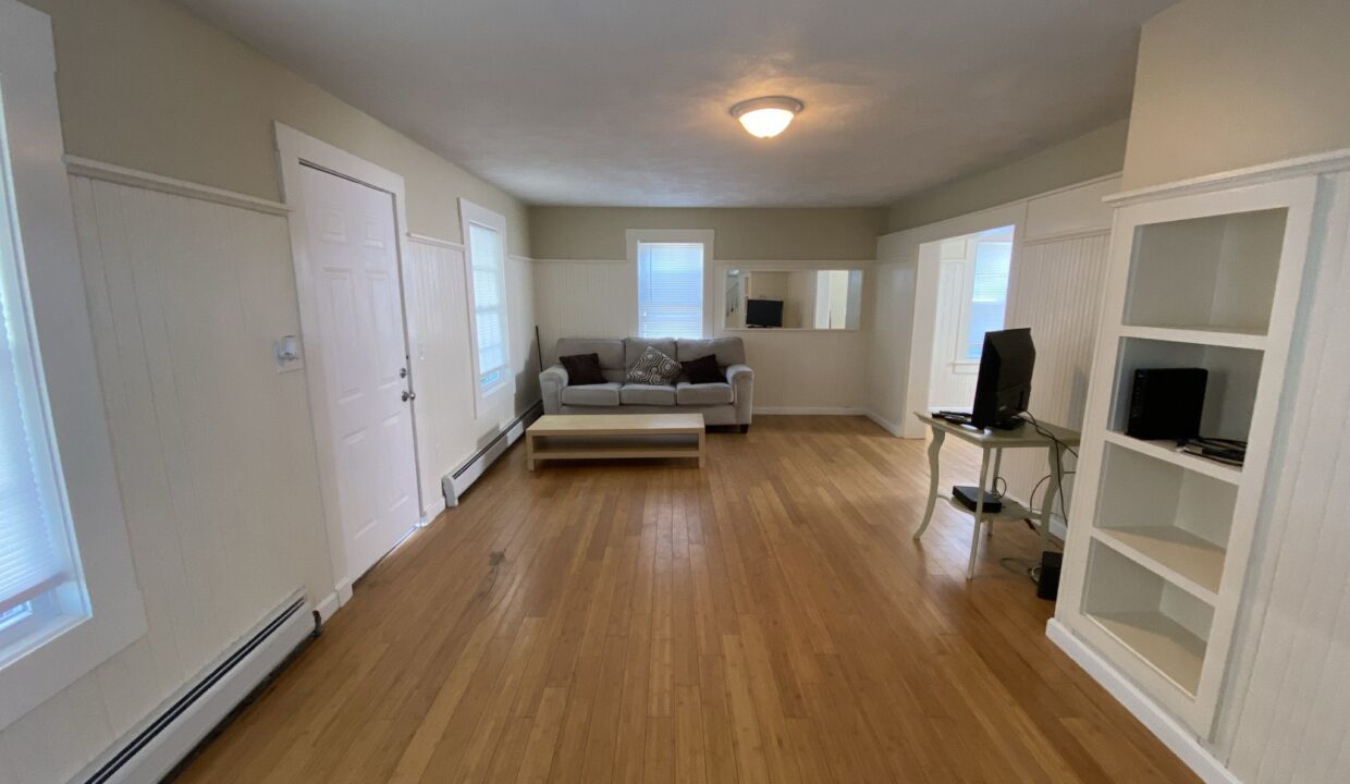 a living room with hard wood floors and white walls.