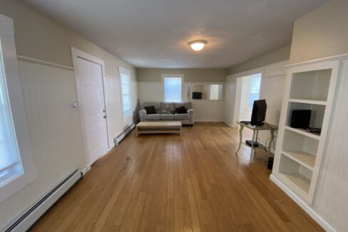 a living room with hard wood floors and white walls.