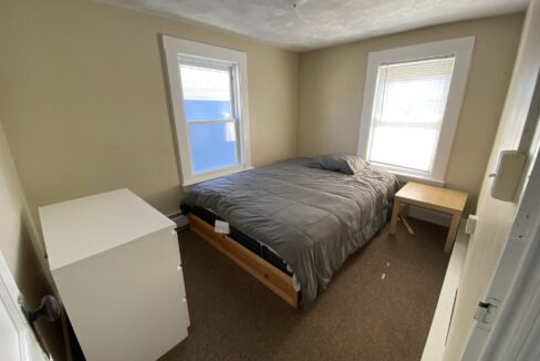 a bedroom with a bed and two windows.