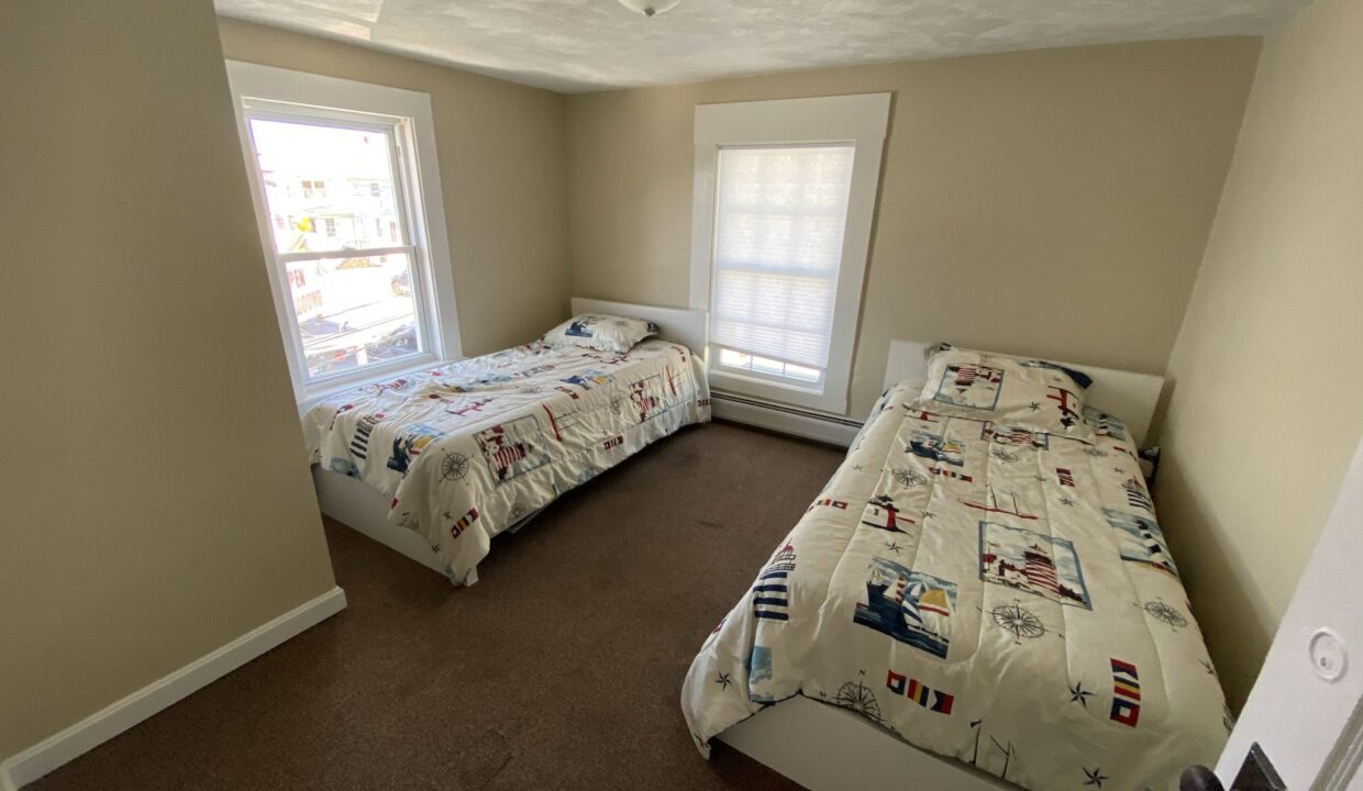 a couple of beds sitting in a bedroom next to a window.