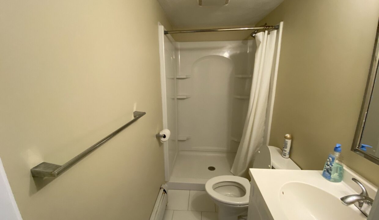 a bathroom with a toilet, sink, and shower.