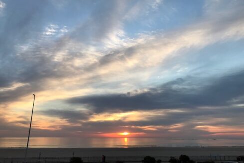 a parking lot next to a beach with a sunset in the background.