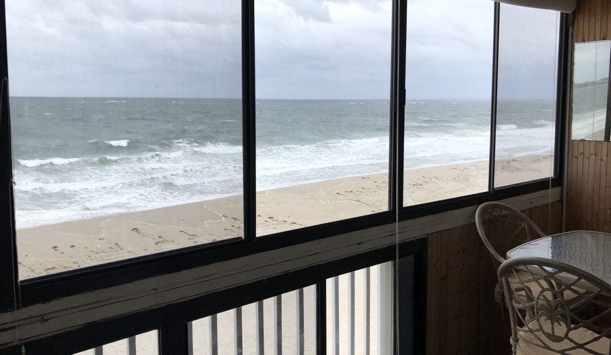 a balcony with a table and chairs overlooking the ocean.