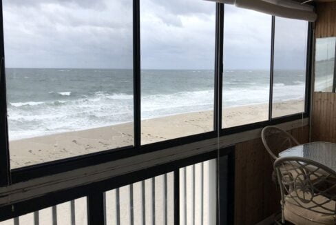 a balcony with a table and chairs overlooking the ocean.