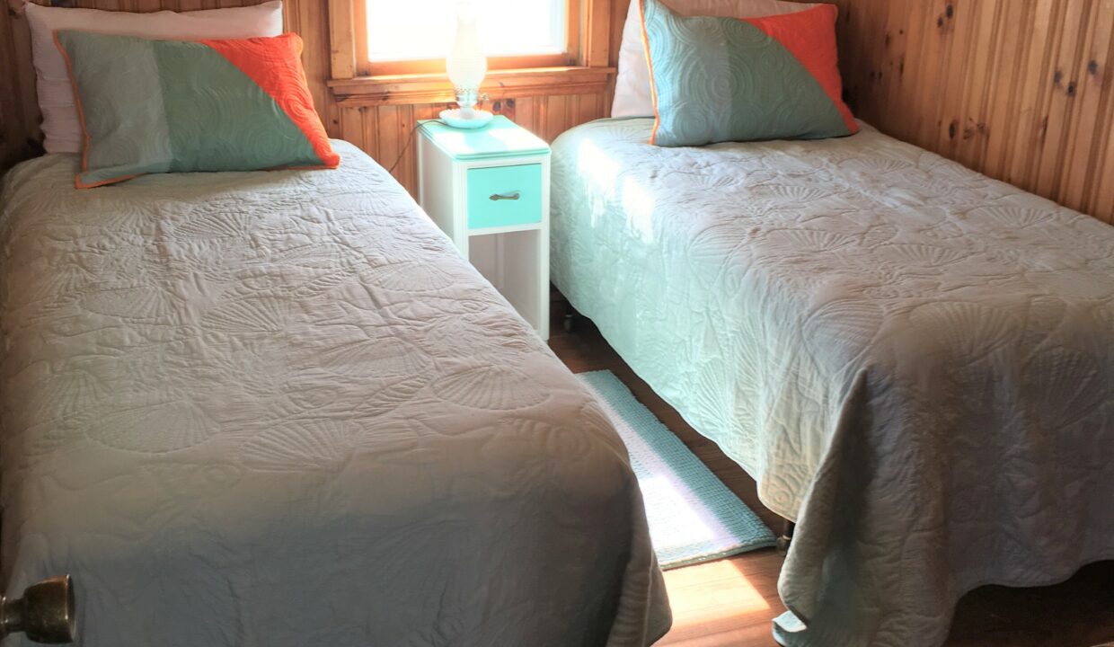 a couple of beds sitting in a bedroom next to a window.