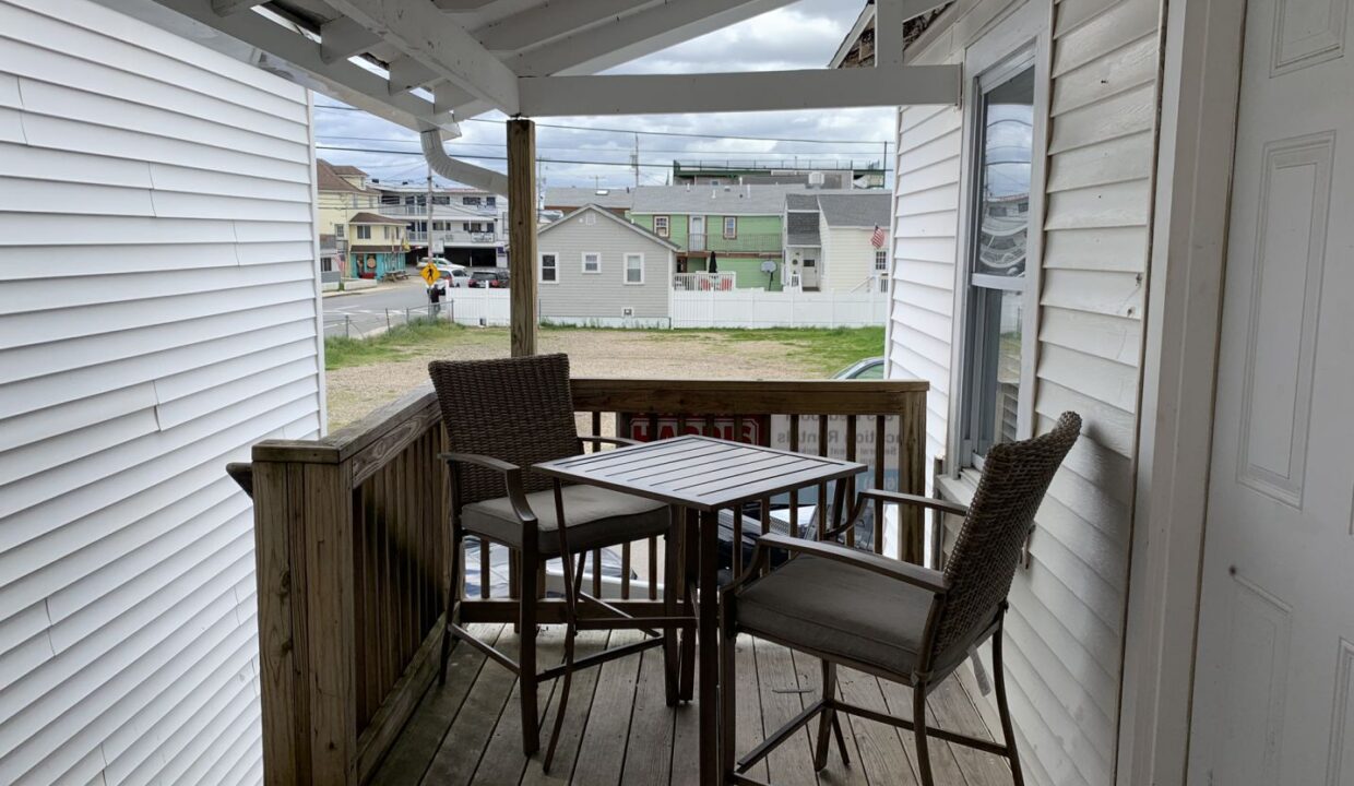 a porch with a table and chairs on it.