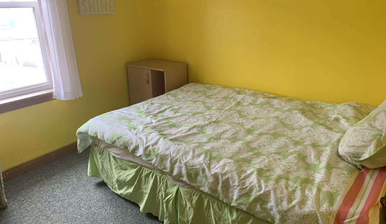 a bedroom with yellow walls and a green bedspread.