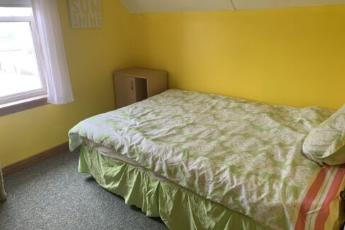 a bedroom with yellow walls and a green bedspread.