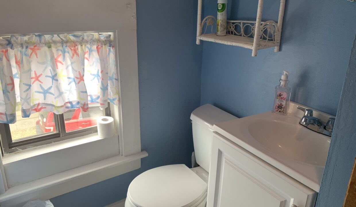 a white toilet sitting next to a window in a bathroom.