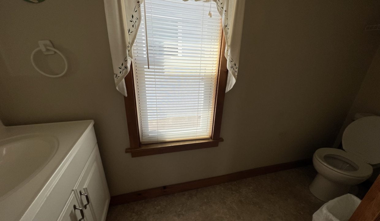 a bathroom with a sink, toilet, and window.