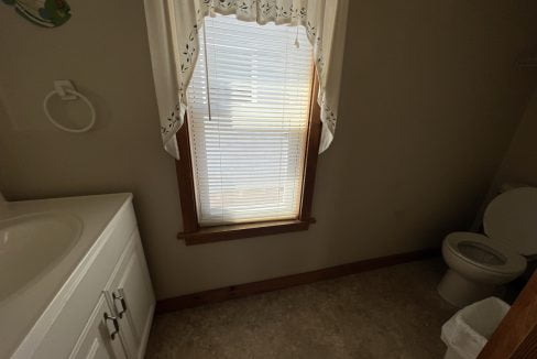 a bathroom with a sink, toilet, and window.