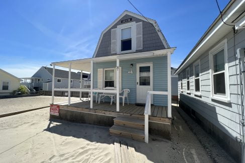 a small house with a porch and steps leading to the front door.