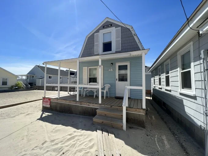 a small house with a porch and steps leading to the front door.