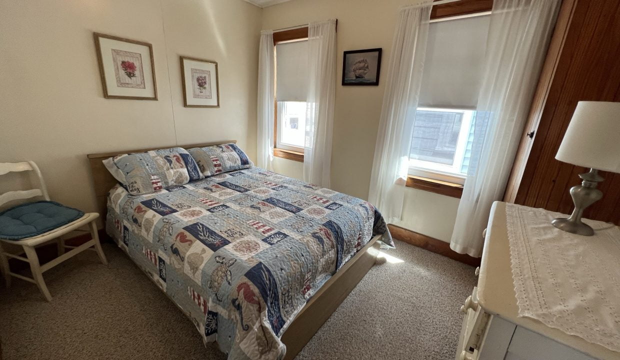 a bed room with a neatly made bed and a chair.