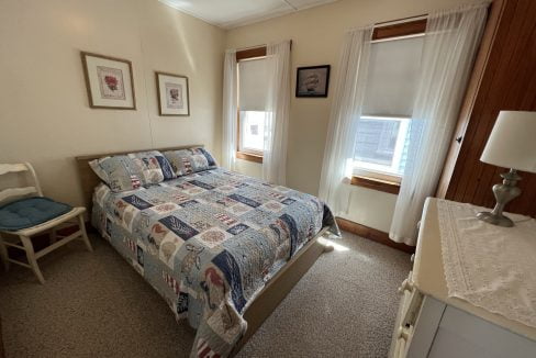 a bed room with a neatly made bed and a chair.