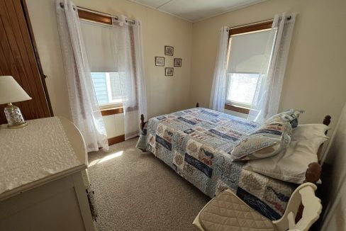 a bed room with a neatly made bed and a chair.