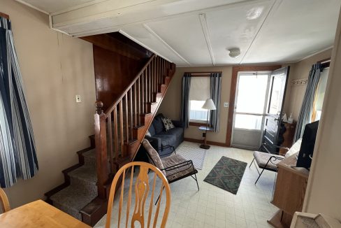 a living room filled with furniture and a wooden staircase.