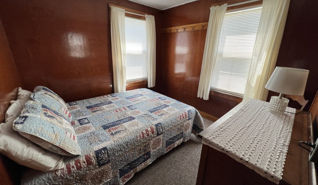 a bed sitting in a bedroom next to two windows.