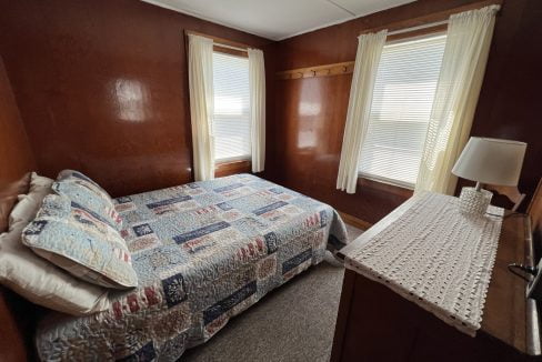 a bed sitting in a bedroom next to two windows.