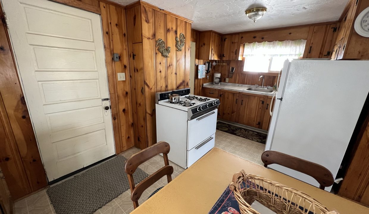 a kitchen with a table, stove, and refrigerator.