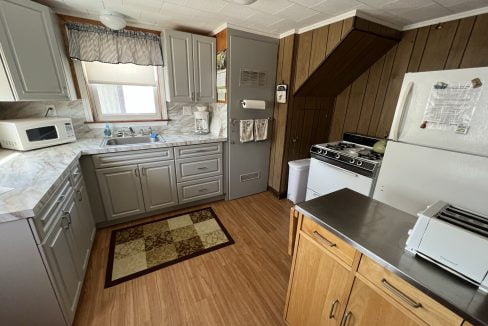 a kitchen with a stove, refrigerator, microwave, and sink.
