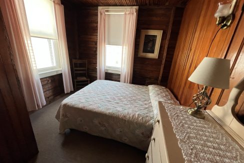 a bedroom with wood paneling and a white bed.