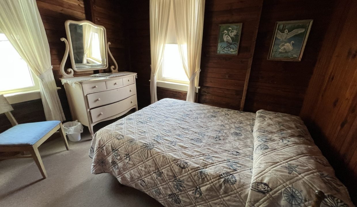 a bedroom with a bed, dresser and mirror.