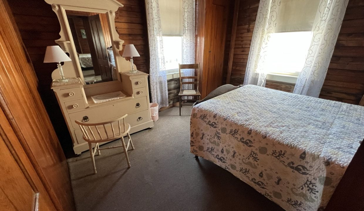 a bedroom with a bed, dresser and mirror.