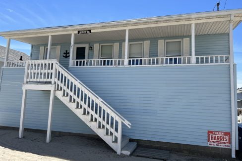 a blue house with a white staircase leading to the second floor.