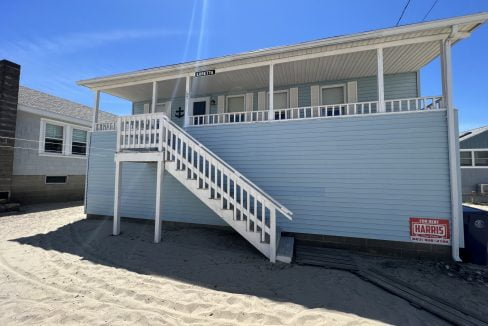 a beach house with a white staircase leading up to it.